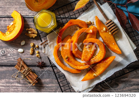 Pumpkin dessert. Baked pumpkin slices with honey, cinnamon and walnuts on a rustic table. Top view flat lay background. 123694320