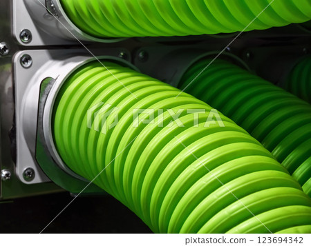Bright green hoses attached to machinery in an industrial setting showing intricate details and smooth curves 123694342