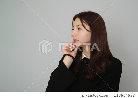 Pensive young woman with a hand on her cheek, gazing away thoughtfully. Represents the contemplation of life's decisions or future plans. Pensive young woman with a hand on her cheek, gazing away thoughtfully. Represents the contemplation of life's decisions or future plans. 123694658