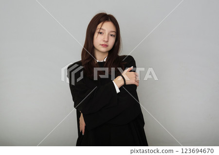 Serene woman embracing herself in a chic black outfit, exuding self-love and confidence against a soft background. 123694670