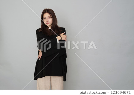 Contemplative young female hugging herself, portrays comfort and self-assurance in a minimalist fashion statement. 123694671