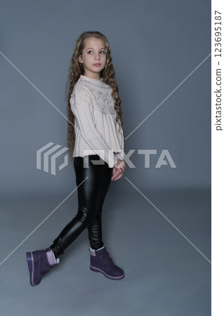 The young girl stands with a hand on her hip, gazing forward with a calm expression. This image showcases her confidence and style, reflecting a modern yet timeless approach to youth fashion. The young girl stands with a hand on her hip, gazing forward with a calm expression. This image showcases her confidence and style, reflecting a modern yet timeless approach to youth fashion. 123695187