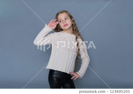 A young girl with flowing curls poses softly in a cozy sweater, with her hand resting gently on her face. This image promotes natural hair care for children, highlighting the beauty of healthy A young girl with flowing curls poses softly in a cozy sweater, with her hand resting gently on her face. This image promotes natural hair care for children, highlighting the beauty of healthy 123695203