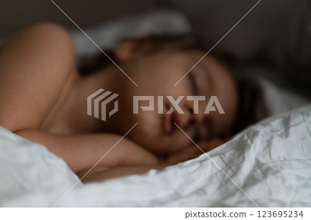 Young boy rests soundly in bed, wrapped in soft blankets, creating a calm and cozy atmosphere. 123695234