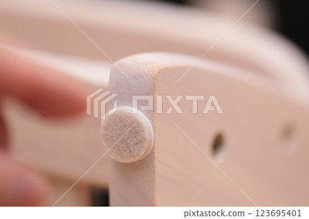 A man putting anti-scratch stickers on the legs of his desk chair 123695401