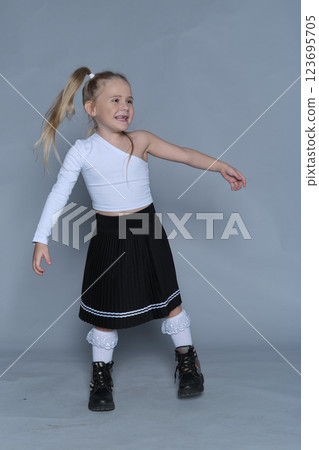 In this studio shot, a confident young girl stands proudly, embodying the spirit of boldness and fearless self-expression. Her trendy outfit complements the concept of embracing individuality at any 123695705