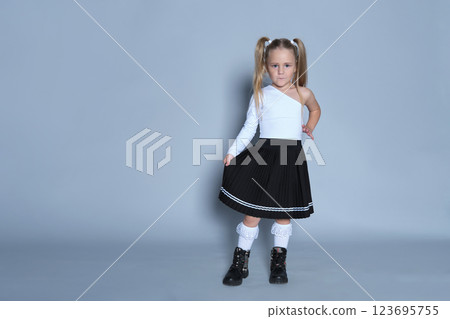 confident young girl stands against a grey background, showing off her fashionable and playful style. The simple backdrop highlights her personality, while her pose reflects a mixture of fun and confident young girl stands against a grey background, showing off her fashionable and playful style. The simple backdrop highlights her personality, while her pose reflects a mixture of fun and 123695755