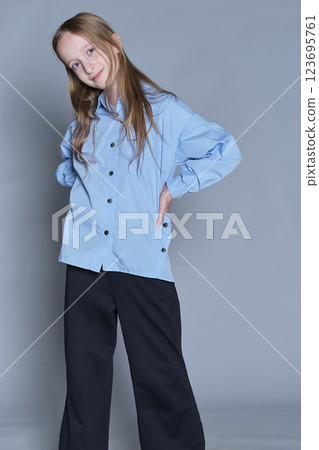 Radiant child with a commanding stance, wearing chic clothes. Ideal for expressing individuality and fashion-conscious youth. 123695761