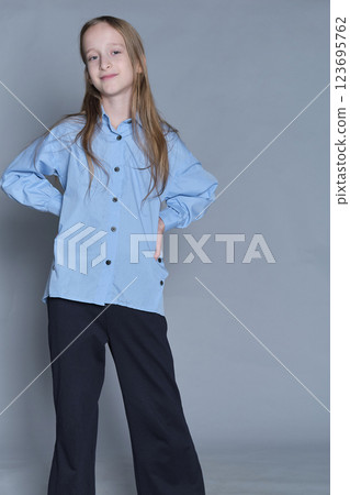 Happy young girl in a classic pose, dressed in smart attire. Represents youthful optimism and modern children s style. 123695762