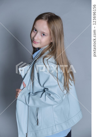 Girl glancing back, her light blue jacket adding a touch of style. Perfect for themes of curiosity and youthful fashion. Girl glancing back, her light blue jacket adding a touch of style. Perfect for themes of curiosity and youthful fashion. 123696156