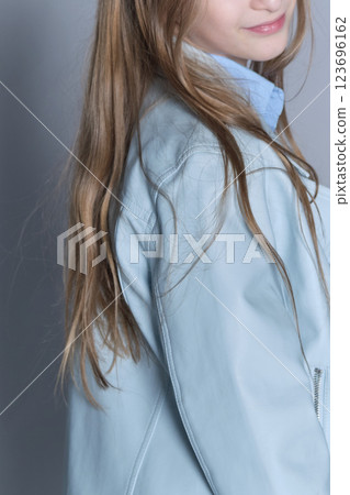 A candid shot of a girl in trendy attire, her gaze inviting and warm. Reflects the casual elegance in children's clothing lines. A candid shot of a girl in trendy attire, her gaze inviting and warm. Reflects the casual elegance in children's clothing lines. 123696162