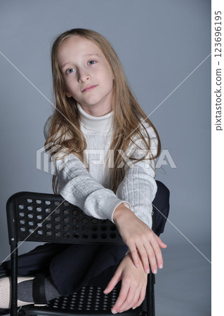 Young girl s tranquil expression as she lounges, the texture of her sweater suggesting softness and warmth. Ideal for winter wear. Young girl s tranquil expression as she lounges, the texture of her sweater suggesting softness and warmth. Ideal for winter wear. 123696195