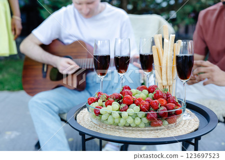 Multiracial group of friends is playing guitar, singing songs at dinner party in summer picnic 123697523