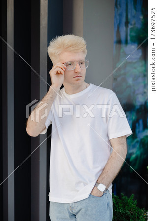 Young man standing outdoors in the street in summer time Young man standing outdoors in the street in summer time 123697525