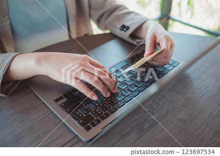 Woman holding credit card while using laptop and shopping outdoor at coffee shop, 123697534
