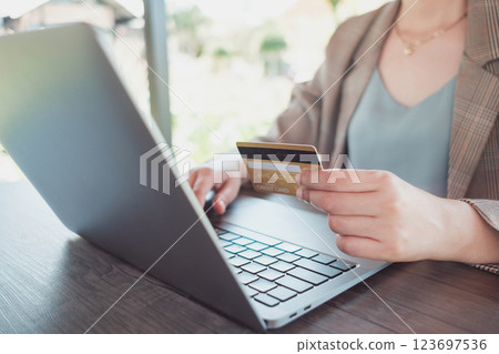 Woman holding credit card while using laptop and shopping outdoor at coffee shop, Woman holding credit card while using laptop and shopping outdoor at coffee shop, 123697536