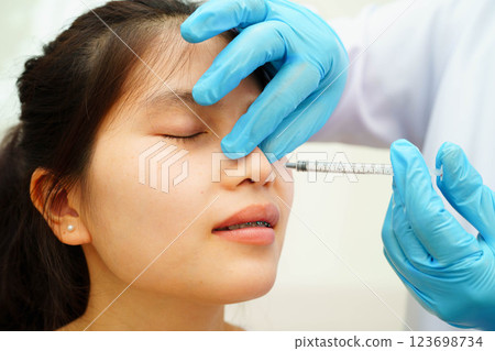 Asian woman receiving plastic surgery shape of nose performed on face. 123698734
