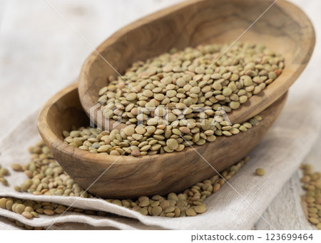 Wooden bowls full of dried raw green lentils on white table closeup. Traditional mediterranean legume Wooden bowls full of dried raw green lentils on white table closeup. Traditional mediterranean legume 123699464