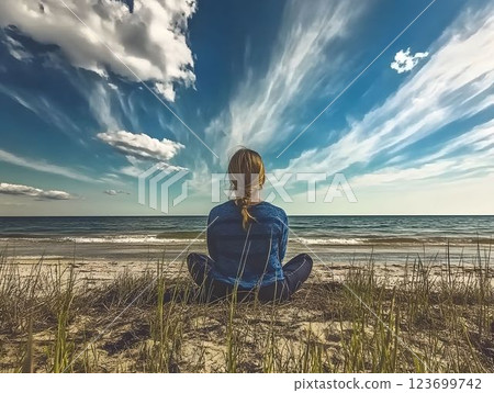 Serene female practicing yoga near ocean waves, meditating with mindful posture against cloudy coastal landscape, embodying wellness and tranquility 123699742