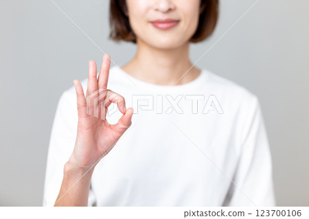 A middle-aged woman smiling and making a circle sign gesture A middle-aged woman smiling and making a circle sign gesture 123700106