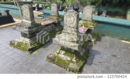 Ancient ancestors javanese king and queen burial in remote jawa, Indonesia, traditional moss-covered stone graves decorated with pink flower petals 123700424