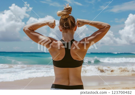 Rear view of fit woman flexing muscles on the beach during summer morning workout.AI Generative. 123700482