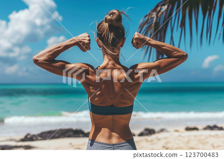 Rear view of fit woman flexing muscles on the beach during summer morning workout.AI Generative. 123700483