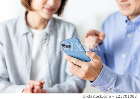A middle-aged couple having a pleasant conversation while looking at their smartphones at home 123701098