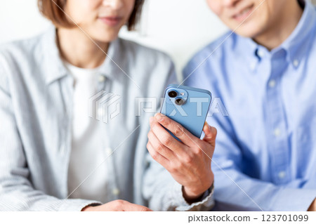 A middle-aged couple having a pleasant conversation while looking at their smartphones at home A middle-aged couple having a pleasant conversation while looking at their smartphones at home 123701099