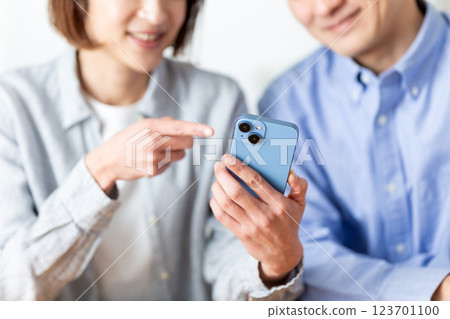 A middle-aged couple having a pleasant conversation while looking at their smartphones at home A middle-aged couple having a pleasant conversation while looking at their smartphones at home 123701100