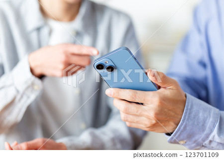 一對中年夫婦在家中一邊看著智慧型手機一邊愉快地交談 123701109