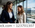 Two professionally dressed women are having a friendly conversation in a modern office setting. Generative ai. 123701307