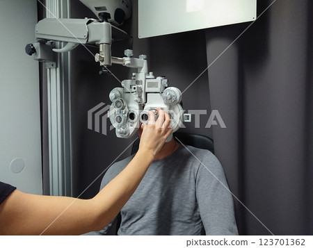 Man in professional clinic wearing phoropter for eye assessment, vision test, and precise lens measurements. Vision improvement concept 123701362