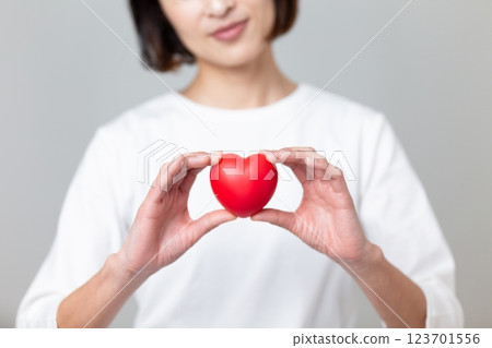 A middle-aged woman worried about holding a heart symbol 123701556