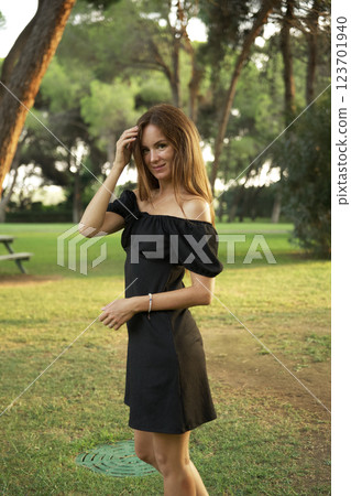Woman in black dress posing in park during sunset Woman in black dress posing in park during sunset 123701940