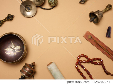 Tibetan singing copper bowl with a wooden clapper on a brown background, objects for meditation and alternative medicine, top view 123702267