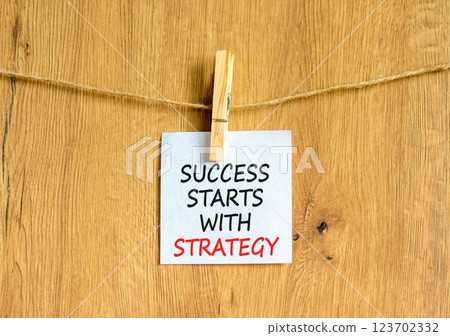 Success starts with strategy symbol. Concept words Success starts with strategy on beautiful white paper. Beautiful wooden background. Business and success starts with strategy concept. Copy space. Success starts with strategy symbol. Concept words Success starts with strategy on beautiful white paper. Beautiful wooden background. Business and success starts with strategy concept. Copy space. 123702332