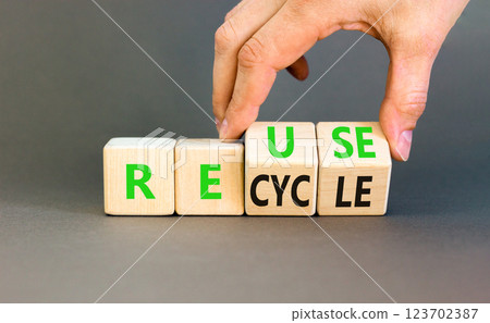 Reuse or recycle symbol. Concept words Reuse Recycle on wooden block. Beautiful grey table grey background. Businessman hand. Business reuse or recycle concept. Copy space. 123702387