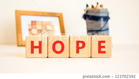 Hope symbol. Concept word Hope on beautiful wooden blocks. Beautiful picture frame and colored pencils. Beautiful white table white background. Business, lifestyle, support hope concept. Copy space. Hope symbol. Concept word Hope on beautiful wooden blocks. Beautiful picture frame and colored pencils. Beautiful white table white background. Business, lifestyle, support hope concept. Copy space. 123702392