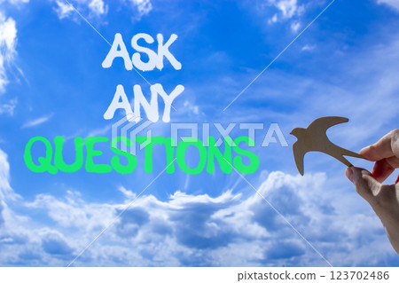 Ask any questions symbol. Concept words Ask any questions on beautiful blue sky. Beautiful blue sky and clouds background. Businessman hand. Wooden bird. Business ask any questions concept. Copy space 123702486