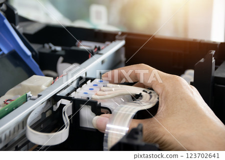 The technician is aligning the print head and repairing the printer. The technician is aligning the print head and repairing the printer. 123702641