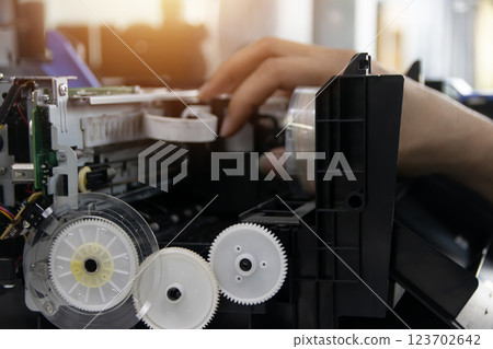 The technician is repairing the printer. The technician is repairing the printer. 123702642