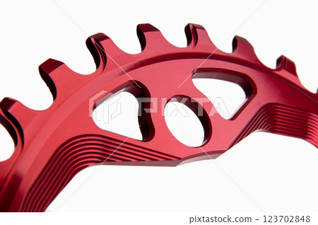 Close up of a red oval bicycle chainring against white isolated background, lies flat on the surface. Professional bicycle part. 123702848