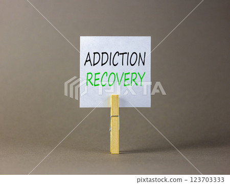 Addiction recovery symbol. Concept words Addiction recovery on beautiful white paper on clothespin. Beautiful grey table grey background. Psychology addiction recovery concept. Copy space. 123703333