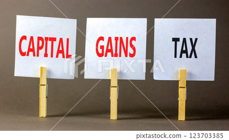 Capital gains tax symbol. Concept words Capital gains tax on beautiful white paper on wooden clothespin. Beautiful grey background. Business and capital gains tax concept. Copy space. 123703385