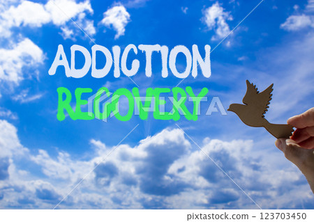Addiction recovery symbol. Concept words Addiction recovery on beautiful blue sky. Psychologist hand, wooden bird. Beautiful blue sky cloud background. Psychology addiction recovery concept Copy space Addiction recovery symbol. Concept words Addiction recovery on beautiful blue sky. Psychologist hand, wooden bird. Beautiful blue sky cloud background. Psychology addiction recovery concept Copy space 123703450