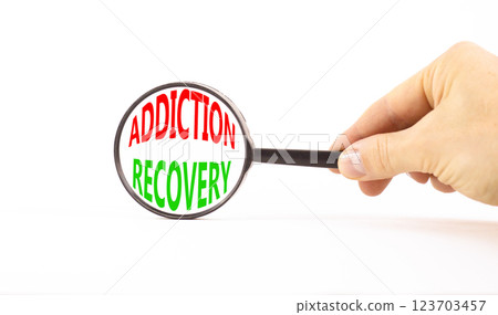 Addiction recovery symbol. Concept words Addiction recovery on beautiful black magnifying glass. Beautiful white table background. Psychologist hand. Psychology addiction recovery concept. Copy space. Addiction recovery symbol. Concept words Addiction recovery on beautiful black magnifying glass. Beautiful white table background. Psychologist hand. Psychology addiction recovery concept. Copy space. 123703457