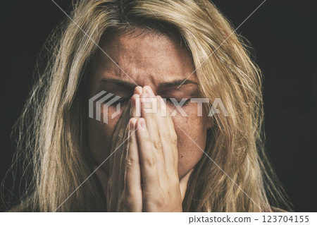 Stress, anxiety and depression with a mental health woman suffering from a headache or migraine in a studio on a dark background. Cancer and sad young female covering her face in fear and distress 123704155