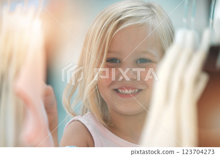 Fashion, girl and happy shopping child at shopping mall store, boutique or retail shop for discount sales clothes on rack. Happiness, smile and young kid or youth customer looking at fabric product 123704273