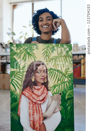 Art, portrait and woman with pride in her painting while working at a creative studio. Happy Indian artist, designer or painter while watercolor design with paint on canvas in a professional workshop 123704283